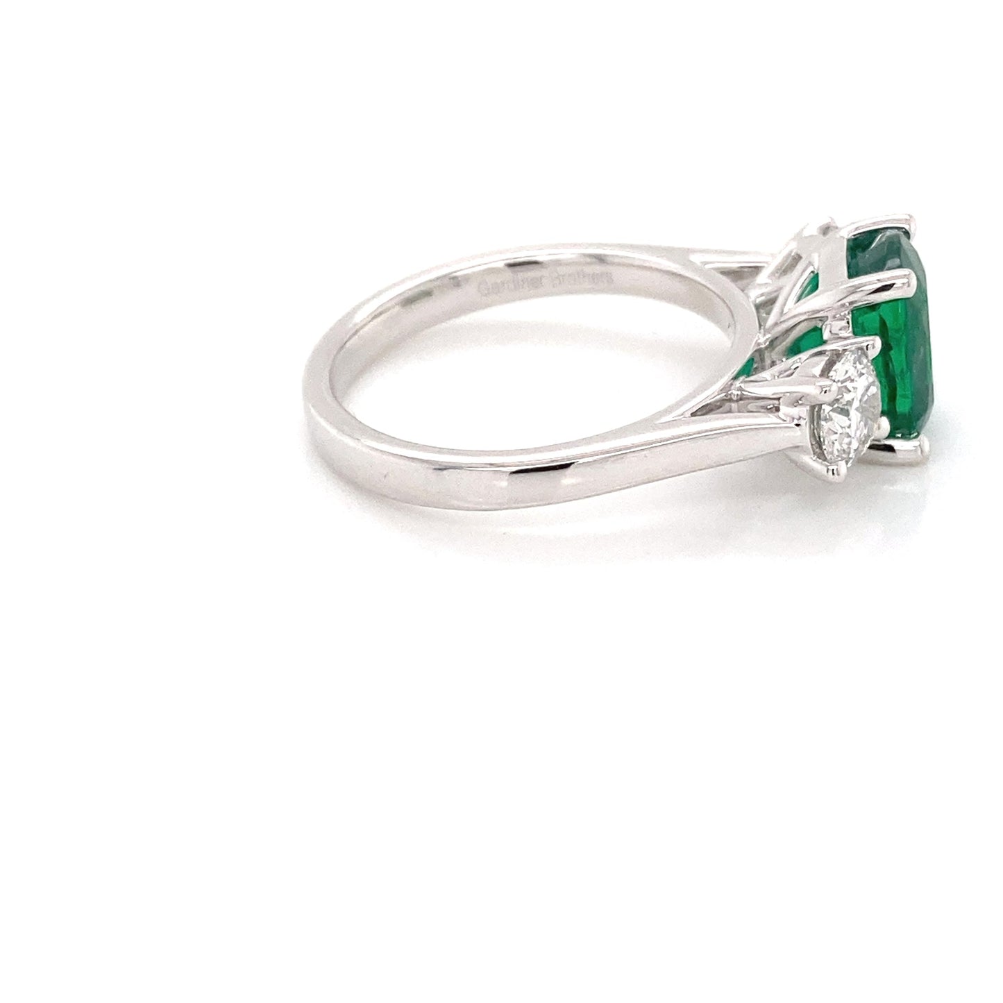 Cushion shaped emerald and round brilliant cut diamond 3 stone ring Gardiner Brothers