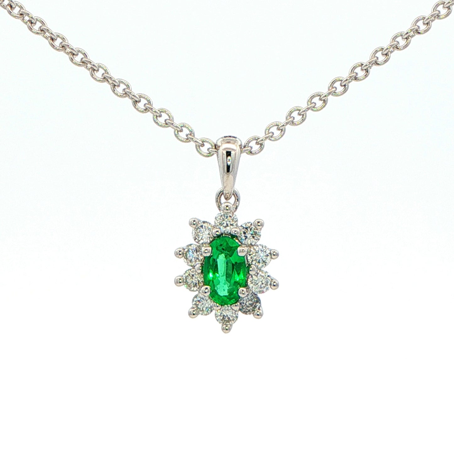 Oval Shaped emerald and round brilliant cut diamond cluster pendant