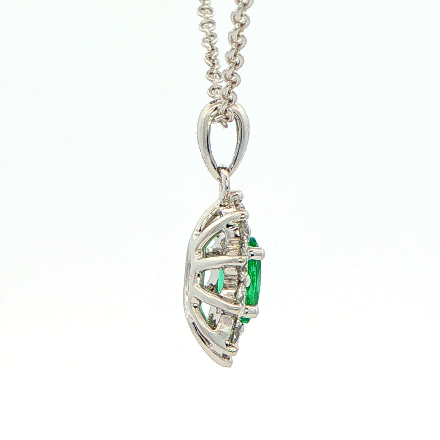 Oval shaped emerald and round brilliant cut diamond cluster pendant
